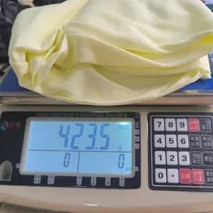 Precision weighing of a yellow pleated dress on a digital scale showing 423.5 grams.