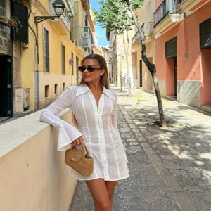 Elegant white textured mini dress with bell sleeves and button details in a street setting