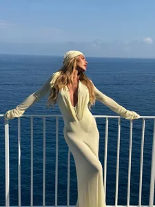 Full view of elegant deep V-neck maxi dress showing pleated waist detail and flared sleeves texture