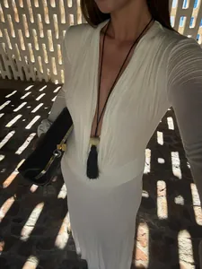 Detail view of white maxi dress showing the deep V-neckline and elegant pleated texture