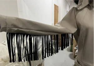 Detail of the black fringe tassel design on the sleeve of a khaki women's ski jumpsuit