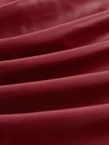 Primo piano macro di materiale in ecopelle rosso scuro con morbide pieghe e trama