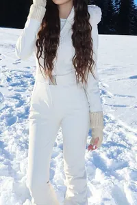 Detailed shot of woman in white hooded one-piece ski suit with fur collar and belt in snow