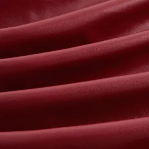 Macro della texture in finta pelle rosso intenso con morbide pieghe per top a fascia.