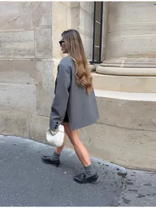 Mujer con americana gris de corte oversize y dobladillo irregular en calle urbana