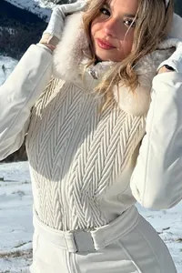 Close-up detail of a white ski jumpsuit featuring a fur collar hood and textured quilting