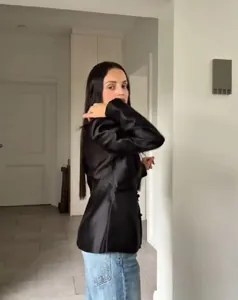 Détail de profil d'une veste en satin noir avec col officier et ourlet en queue de poisson