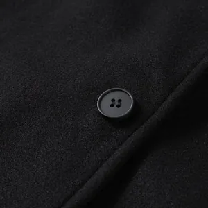 Macro close-up view of premium black wool coat fabric with a classic matte four-hole button.