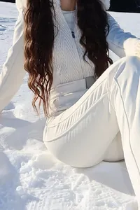 Detail of white hooded ski jumpsuit with belt and fur trim on snow