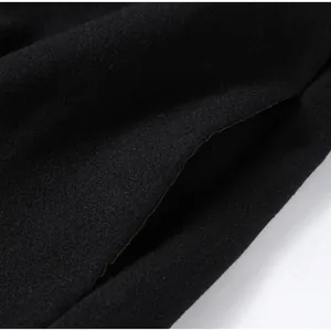Macro detail of a black woolen coat showcasing the premium fabric texture and pocket