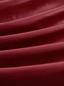 Dettaglio ravvicinato di ecopelle bordeaux con morbidi drappeggi e trama molto fine.