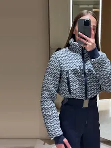 Mirror selfie showing a woman wearing a chic houndstooth ski jacket and belted pants