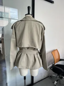 Rückansicht eines kurzen khakifarbenen Trenchcoats mit Gürtel auf einer weißen Schaufensterpuppe