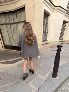 Elegante blazer gris oversize para mujer con dobladillo asimétrico en entorno urbano