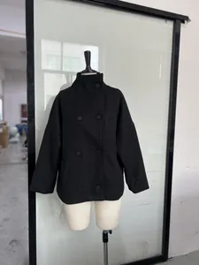 Front view of a black double-breasted wool coat with high stand collar on a mannequin