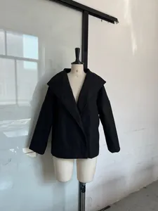 Classic black double-breasted short wool coat with wide collar displayed on mannequin