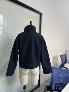 Detail view of a navy blue woolen jacket with a stand-up collar on a mannequin.