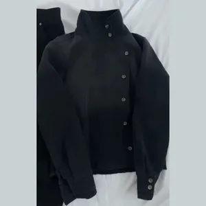 Detail shot of black vintage stand-collar utility jacket with asymmetrical buttons