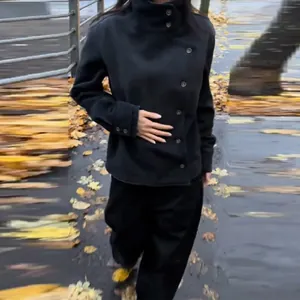 Detail of a vintage black stand-collar jacket with diagonal buttons on a model