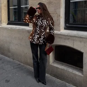Woman wearing a slim fit spotted faux fur jacket with brown fur cuffs on a city street