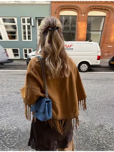 Back view of a stylish brown suede poncho with long fringe detail on a street