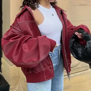 Dettaglio di una giacca oversize in ecopelle bordeaux con cuciture bianche a contrasto.