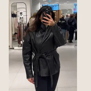 Full body mirror selfie of a black retro lapel belted PU leather jacket for women