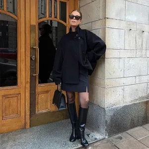 Elegant black stand-collar wool coat styled with a matching mini skirt and boots.