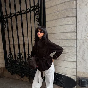 Elegant dark brown suede jacket with waist tie and white trousers on model
