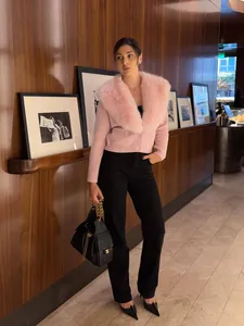 Elegante cardigan in maglia rosa con collo in pelliccia oversize indossato da una modella in interno