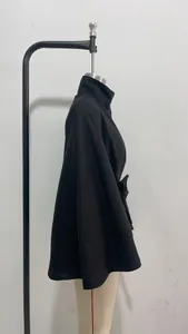 Detalle de perfil lateral de una elegante chaqueta capa negra con diseño de cinturón.