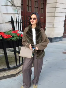 Full view of elegant woman wearing olive green faux fur patchwork cardigan jacket outdoors