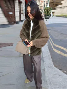 Detail view of a warm jacket featuring eco-fur and knit patchwork worn in an urban street