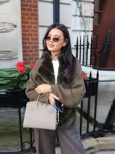 A stylish model wearing an olive green faux fur patchwork cardigan with a cozy fur collar
