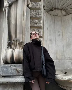 Vista dettagliata di una giacca nera vintage con collo alto, spalline e polsini regolabili