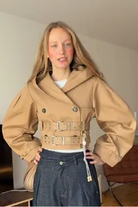 Chique korte trenchcoat met capuchon, pofmouwen en meervoudige ceintuurs in de taille.