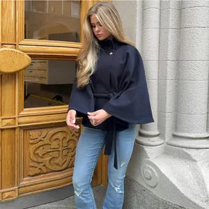 Primer plano de elegante chaqueta tipo capa azul marino con cinturón y botón dorado