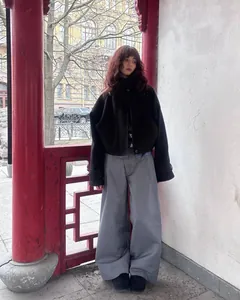 Dettaglio a figura intera di una giacca vintage nera a collo alto e pantaloni larghi