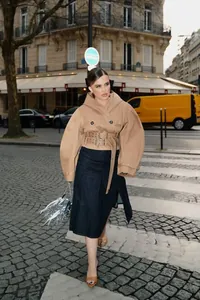 Chique vrouw in een modieuze camel trenchcoat met capuchon tijdens een stadswandeling