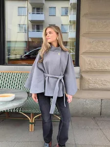 Elegante chaqueta tipo capa gris con botón dorado y cinturón para un look urbano