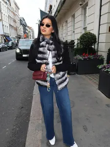 Chic grey and black striped faux fur vest styled with denim jeans in city street view