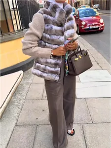 Stylish faux fur patchwork vest for women worn over a knit sweater in street style.