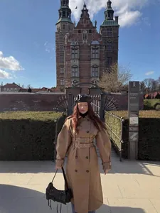 Stijlvolle lange kaki trenchcoat met dubbele riem in een Europese kasteelomgeving