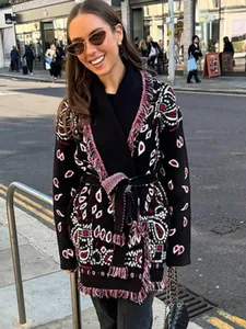 Femme en cardigan en maille ethnique à franges avec ceinture dans la rue