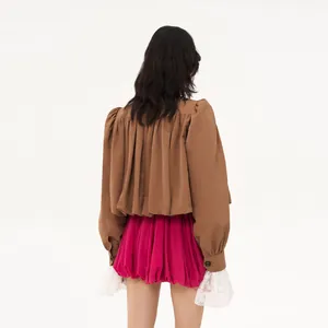 Back view detail of a brown short trench coat with pink bubble skirt and lace cuffs detail