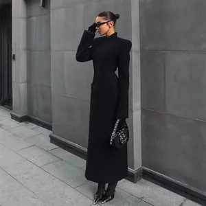Detail view of elegant long black coat with padded shoulders and cinched waist for women.