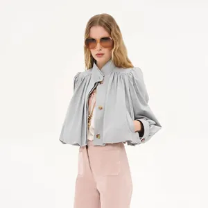 Detailed view of stylish gray cropped trench coat featuring pleated padded shoulders and stand collar