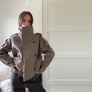 Close-up view of a woman wearing a brown stand collar double-breasted wool jacket.