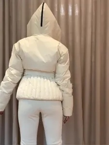 Rückansicht einer cremeweißen Skijacke mit Taillengürtel und abnehmbarer Kapuze Detail.