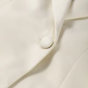 Detailansicht eines cremefarbenen Blazers mit stoffbezogenem Knopf und eleganter Revers
